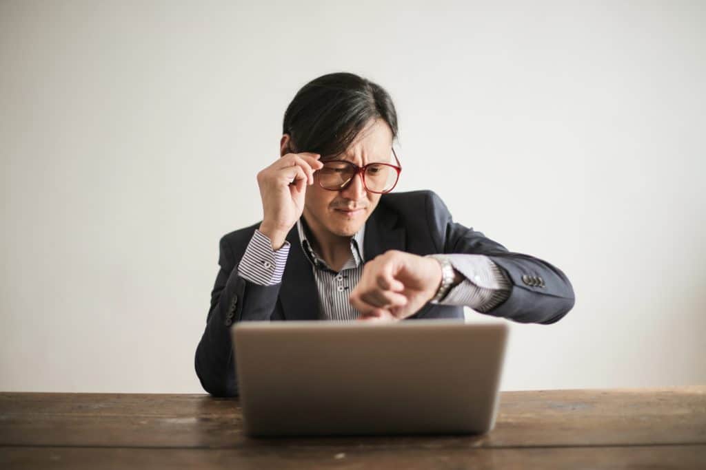 Man at computer looking at watch